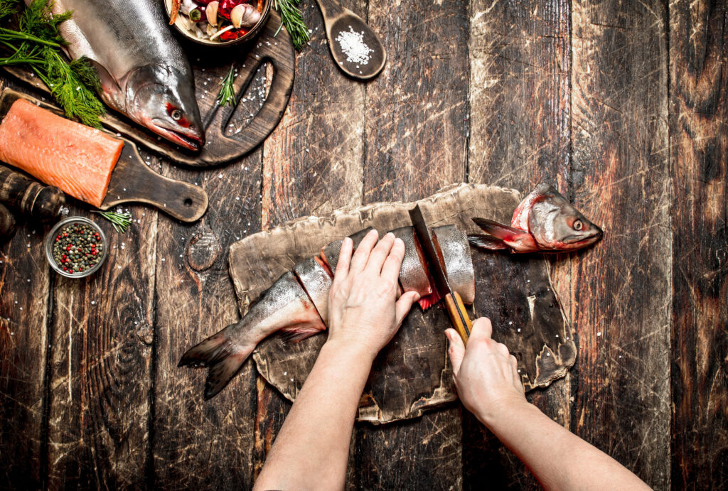 Home chef slicing fish received through reliable fish delivery in Singapore