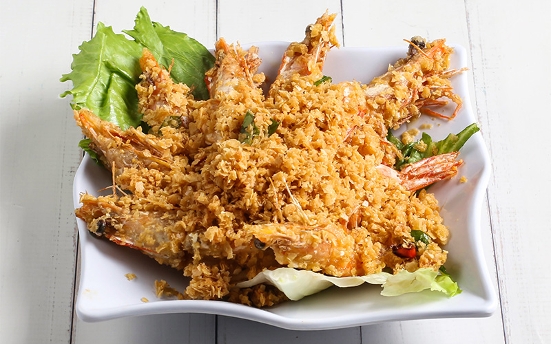 Crispy fried prawns topped with golden cereal flakes on lettuce.